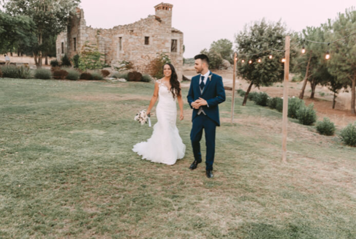 Bride and groom walking together on lawn at rustic outdoor wedding venue Bride and groom walking together on lawn at rustic outdoor wedding venue