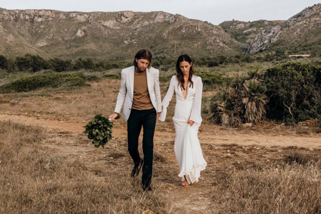 Elopement young man wearing a black suit standing along with his bride